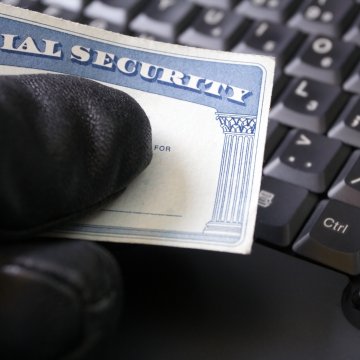 zander id theft protection service overview features hand with black glove holding social security card black computer keyboard in the background